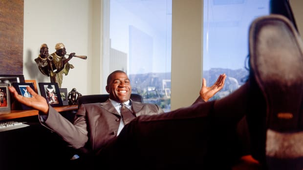 Former Laker Earvin (Magic) Johnson poses at his desk in his office in Beverly Hills, CA in July, 2001.